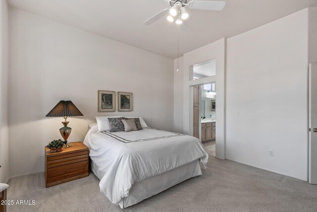 bedroom featuring light carpet, a ceiling fan, and ensuite bath