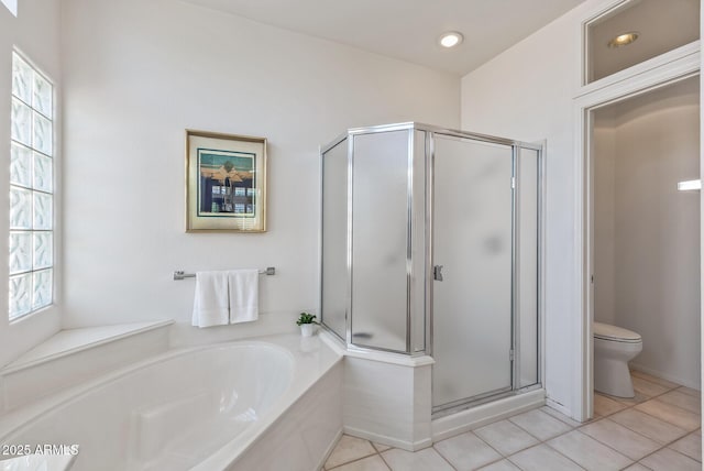 bathroom featuring a garden tub, toilet, a stall shower, and a wealth of natural light