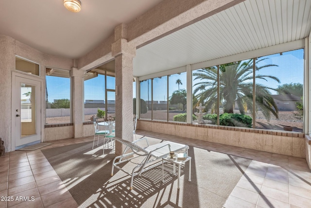 unfurnished sunroom featuring beamed ceiling and tile patterned floors
