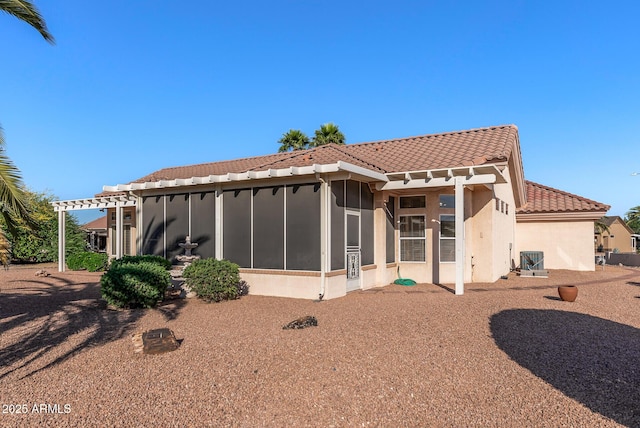 back of property with a sunroom, a tiled roof, and stucco siding