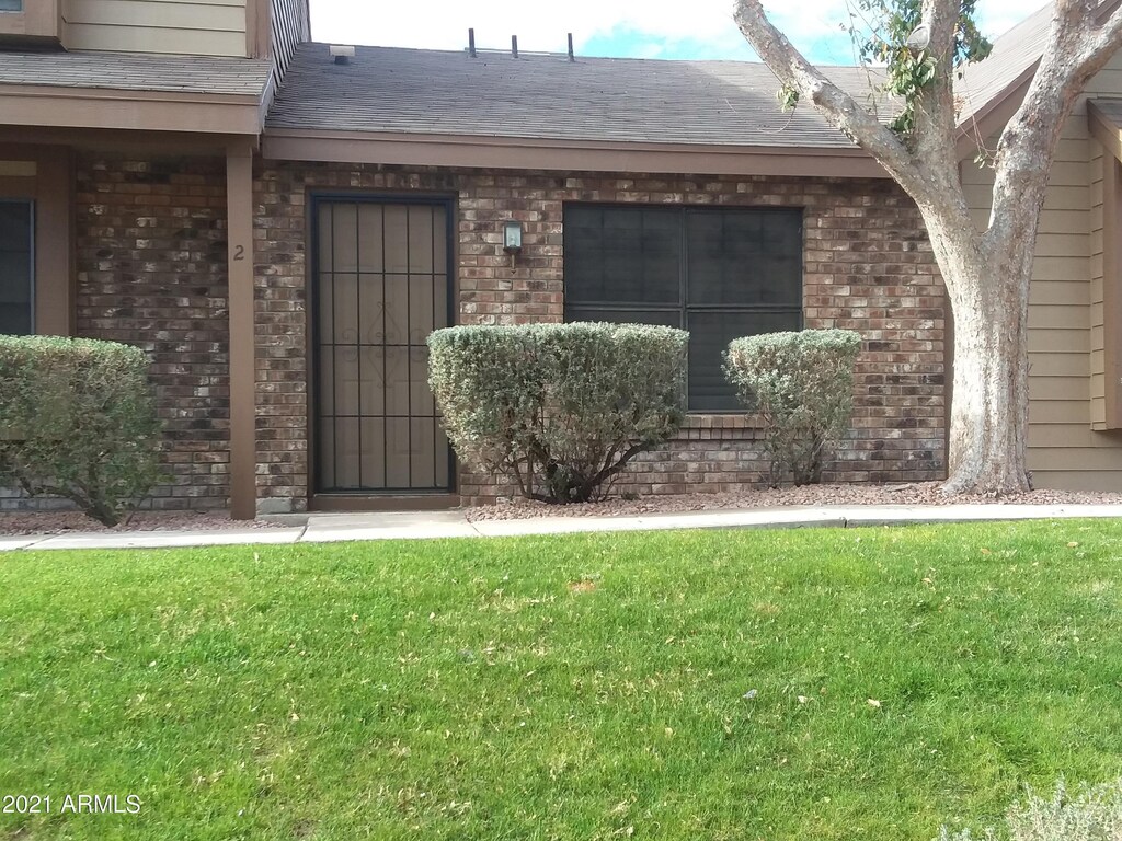 property entrance with a yard, brick siding, and a shingled roof