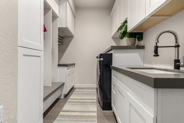 washroom with cabinets, sink, independent washer and dryer, and dark wood-type flooring