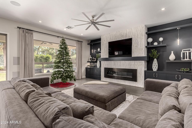 living room with wood-type flooring, a large fireplace, and ceiling fan