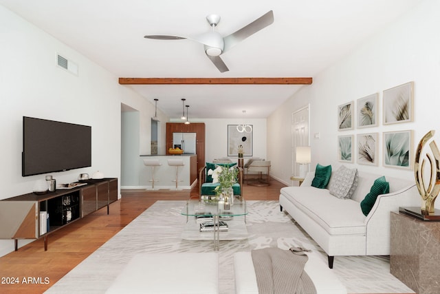 living room with ceiling fan, beamed ceiling, and hardwood / wood-style floors