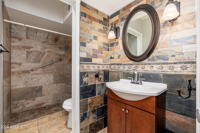 bathroom featuring vanity, tile walls, a tile shower, and toilet