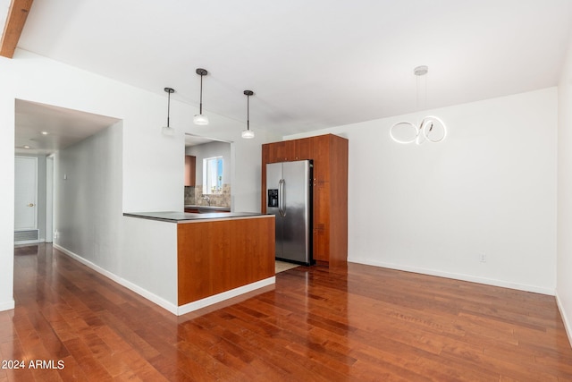 kitchen with stainless steel refrigerator with ice dispenser, hanging light fixtures, dark hardwood / wood-style flooring, and tasteful backsplash