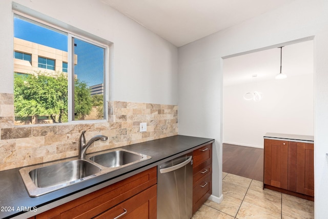 kitchen with light tile patterned flooring, tasteful backsplash, pendant lighting, stainless steel dishwasher, and sink