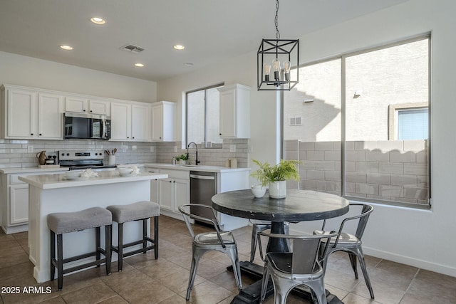 kitchen with white cabinetry, decorative backsplash, stainless steel appliances, and a center island