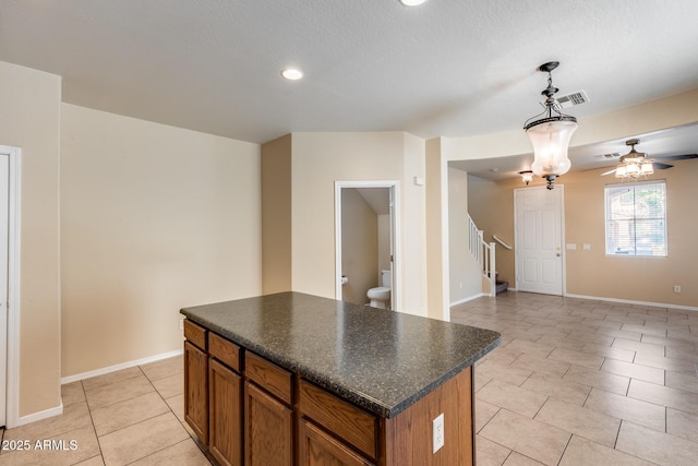 9 N 87th Ln N, Tolleson, AZ 85353 - kitchen featuring dark countertops, light tile patterned flooring, a center island, brown cabinetry, and recessed lighting