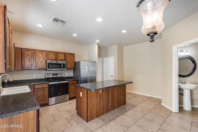 9 N 87th Ln N, Tolleson, AZ 85353 - kitchen featuring appliances with stainless steel finishes, a sink, a center island, brown cabinets, and light tile patterned floors