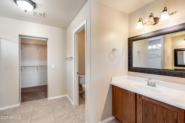 9 N 87th Ln N, Tolleson, AZ 85353 - full bathroom featuring vanity, toilet, baseboards, tile patterned flooring, and a spacious closet