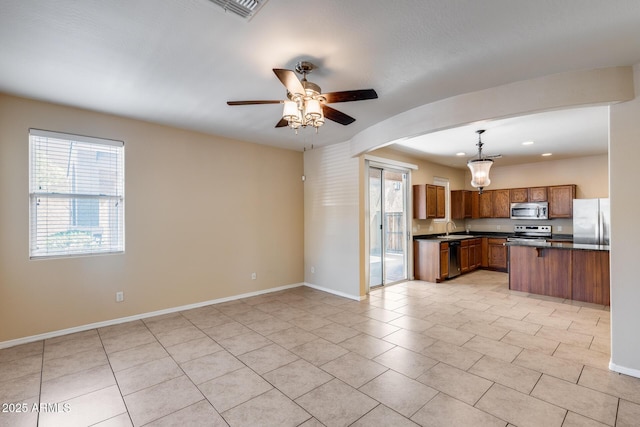 9 N 87th Ln N, Tolleson, AZ 85353 - kitchen with appliances with stainless steel finishes, dark countertops, brown cabinets, open floor plan, and recessed lighting