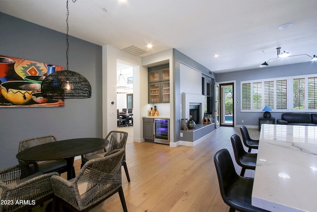 interior space with wine cooler, bar, and light wood-type flooring