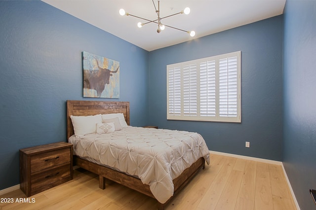 bedroom with light hardwood / wood-style flooring and an inviting chandelier