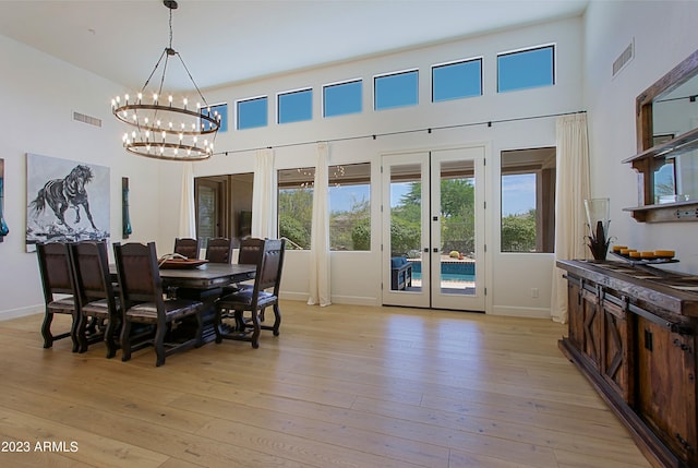 dining space with french doors, a high ceiling, and light wood-type flooring