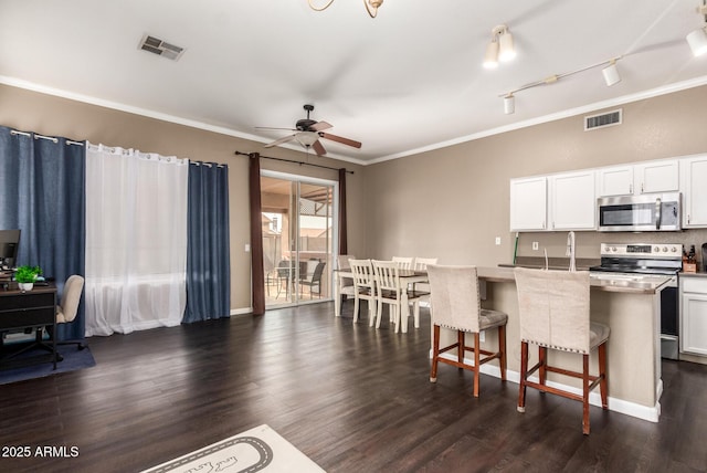 kitchen featuring a center island with sink, a breakfast bar area, white cabinets, and appliances with stainless steel finishes