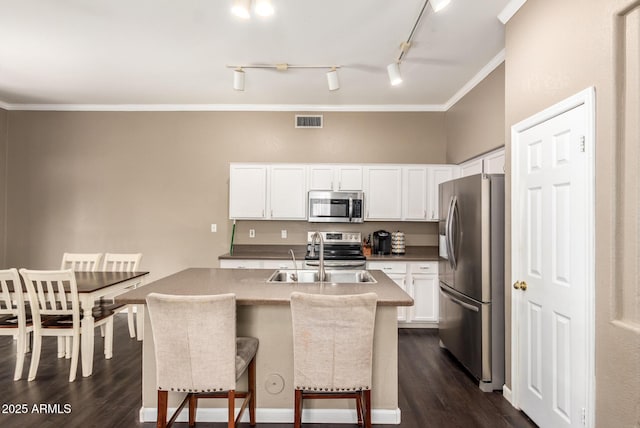 kitchen with sink, white cabinetry, stainless steel appliances, ornamental molding, and a center island with sink