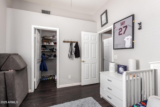 bedroom featuring a walk in closet, dark hardwood / wood-style flooring, and a closet