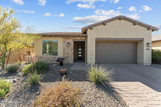 view of front of home featuring a garage, stucco siding, decorative driveway, and brick siding