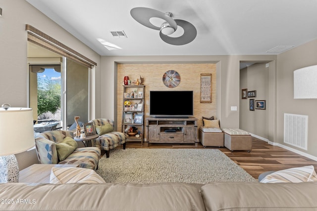 living area featuring baseboards, visible vents, and wood finished floors