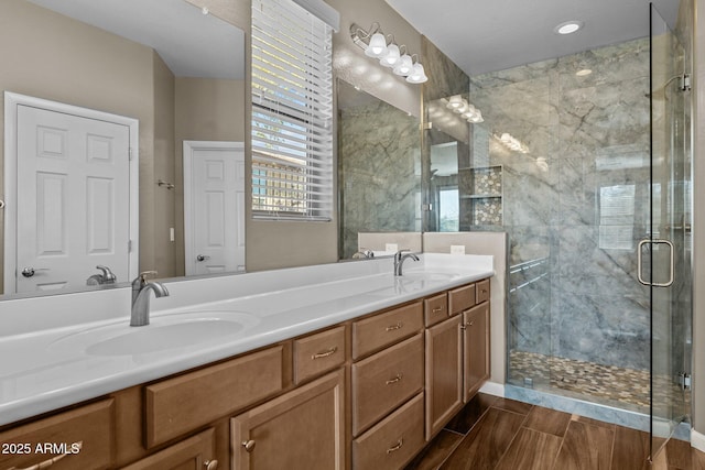 bathroom featuring double vanity, a stall shower, wood tiled floor, and a sink