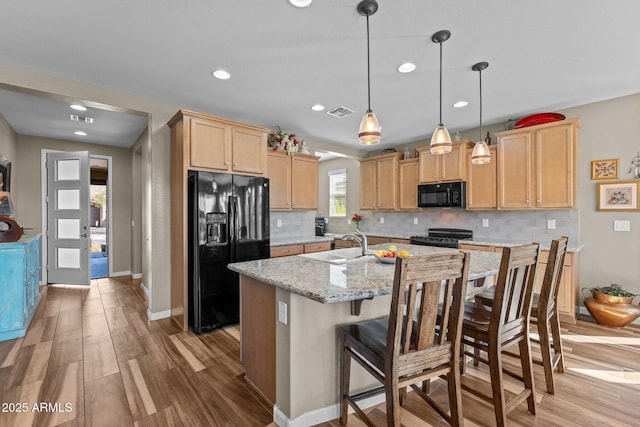 kitchen featuring decorative backsplash, light wood-type flooring, black appliances, and light brown cabinetry