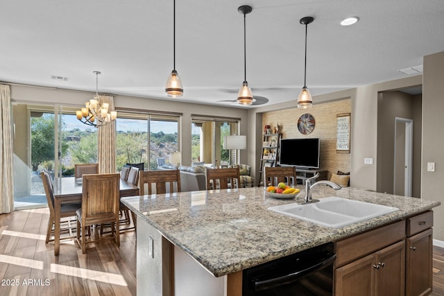 kitchen with wood finished floors, a sink, open floor plan, hanging light fixtures, and dishwasher