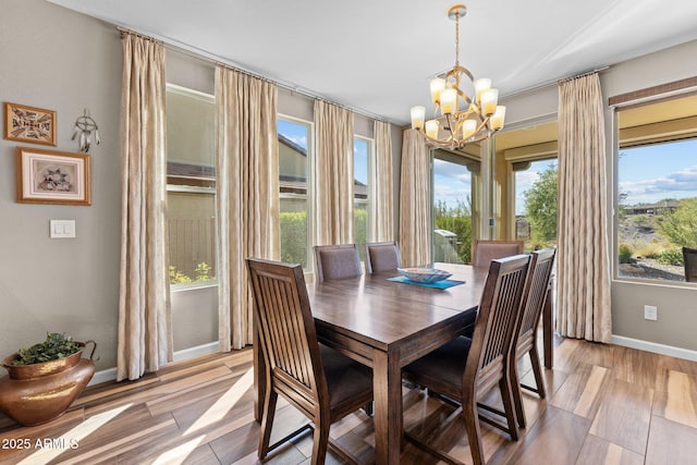 dining area with baseboards, light wood-style floors, and an inviting chandelier