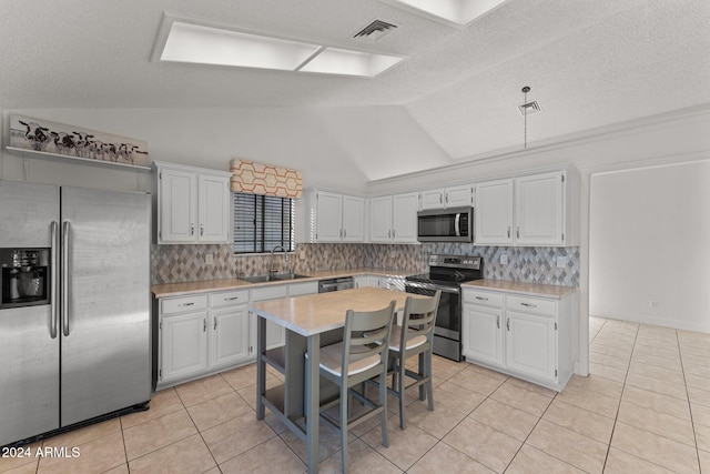 kitchen featuring white cabinetry, appliances with stainless steel finishes, and vaulted ceiling