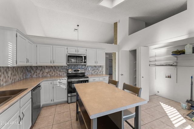 kitchen with light tile patterned flooring, stainless steel appliances, backsplash, high vaulted ceiling, and white cabinets