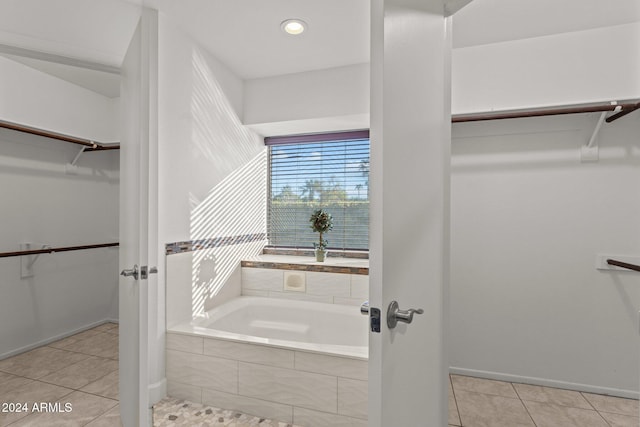 bathroom with tile patterned floors and a relaxing tiled tub