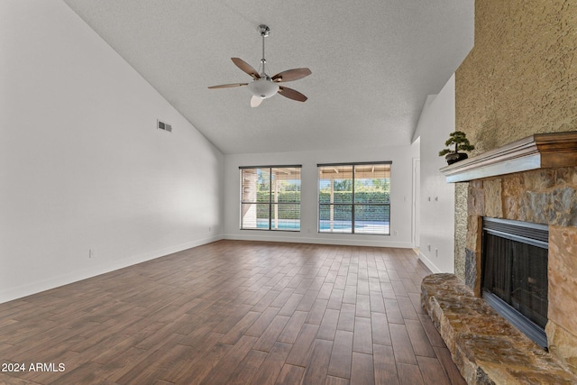 unfurnished living room featuring ceiling fan, dark hardwood / wood-style floors, a textured ceiling, high vaulted ceiling, and a stone fireplace