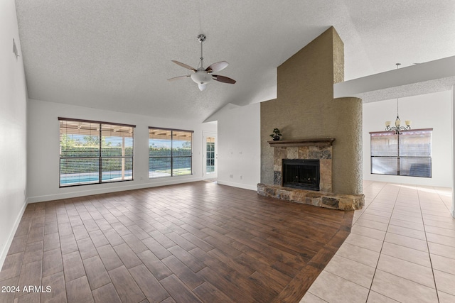 unfurnished living room featuring ceiling fan with notable chandelier, light hardwood / wood-style flooring, a textured ceiling, and a fireplace