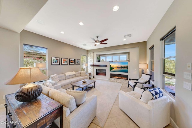 living area with a glass covered fireplace, plenty of natural light, and visible vents