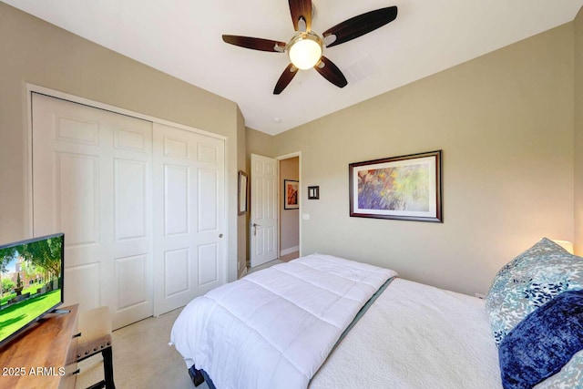 bedroom with ceiling fan, light carpet, and a closet