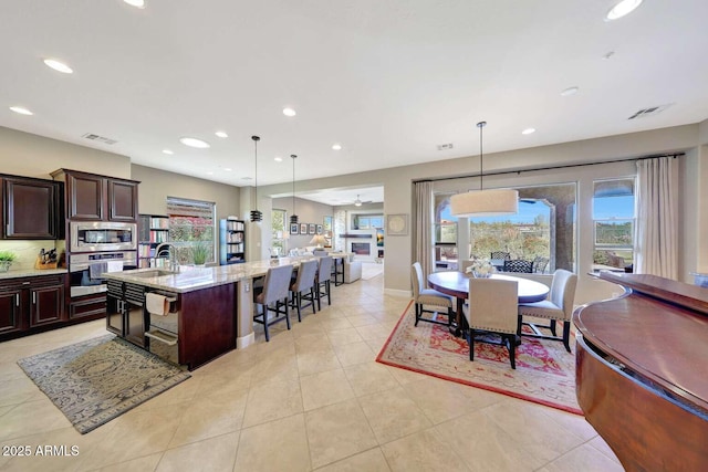 kitchen featuring pendant lighting, appliances with stainless steel finishes, a large island with sink, and visible vents
