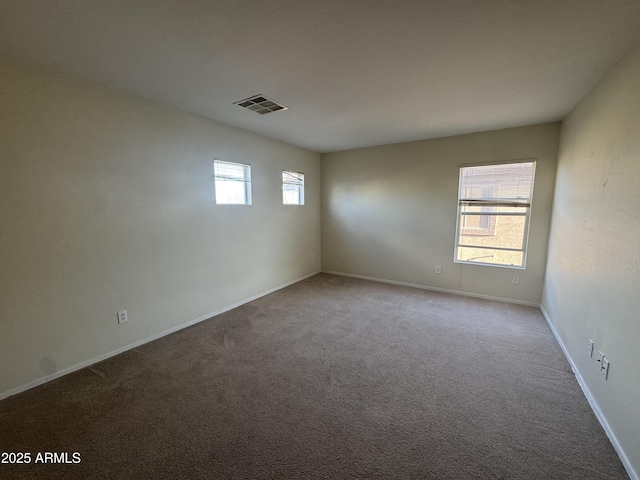 spare room with carpet floors, baseboards, and visible vents