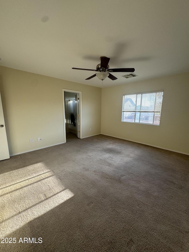 carpeted empty room featuring ceiling fan, visible vents, and baseboards