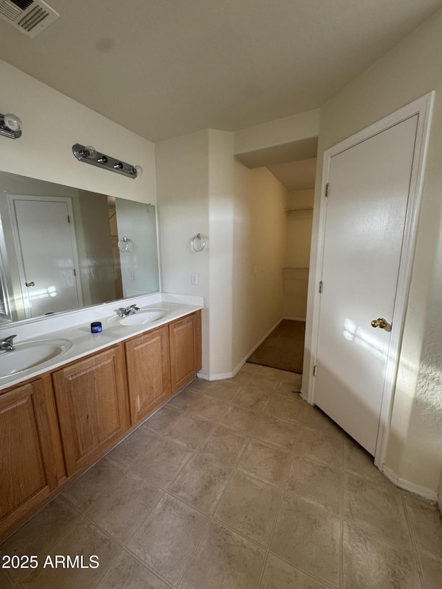 bathroom with visible vents, a sink, baseboards, and double vanity