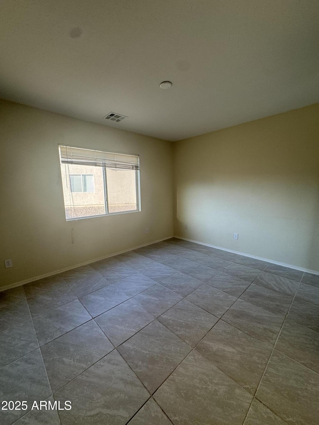 tiled empty room with visible vents and baseboards