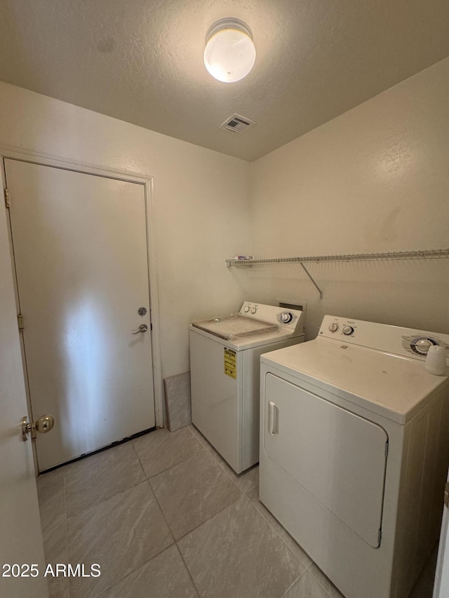 laundry room with washer and dryer, laundry area, a textured ceiling, light tile patterned floors, and visible vents
