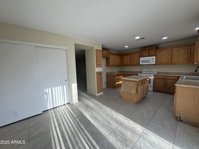 kitchen with a center island, a sink, light countertops, recessed lighting, and white appliances