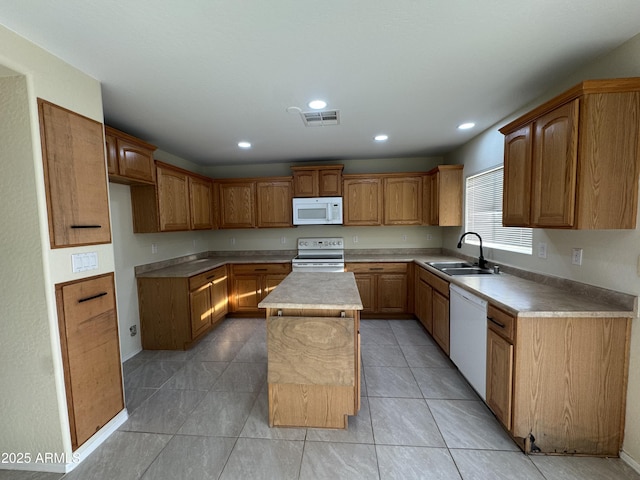 kitchen with a kitchen island, white appliances, recessed lighting, light countertops, and a sink