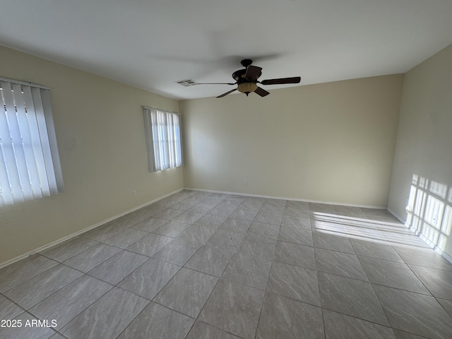 spare room featuring a ceiling fan, tile patterned floors, visible vents, and baseboards