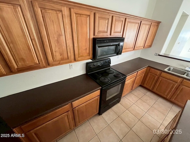 kitchen featuring a sink, dark countertops, light tile patterned flooring, black appliances, and brown cabinets