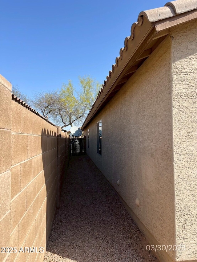 view of home's exterior with a tile roof, stucco siding, and fence