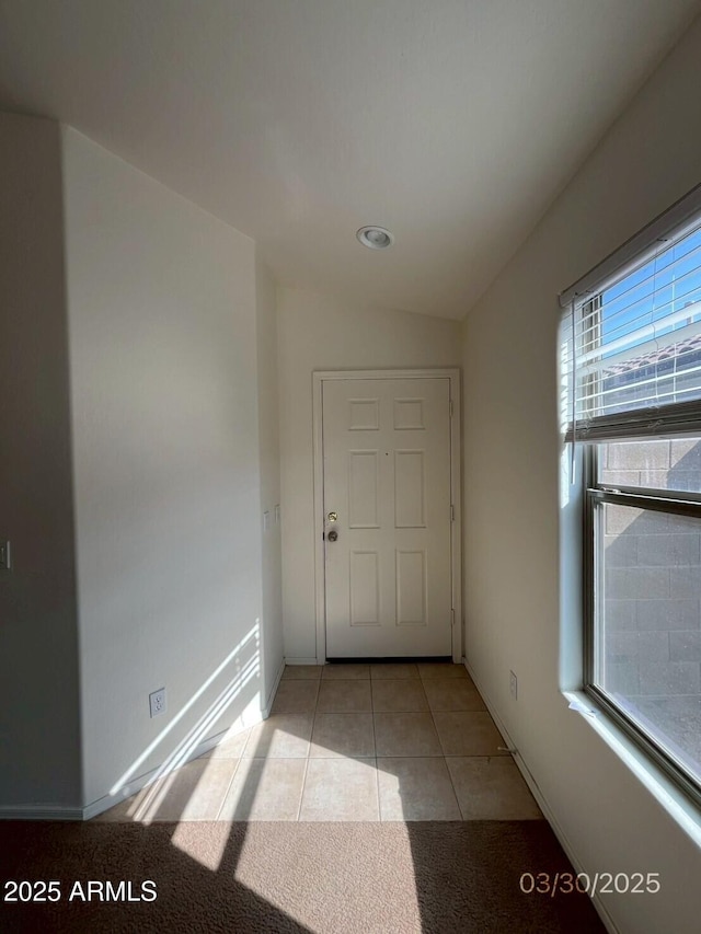 interior space with light tile patterned flooring, baseboards, and lofted ceiling