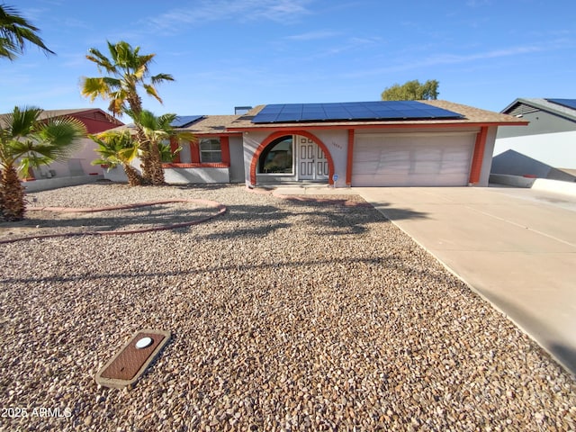 ranch-style house with a garage, solar panels, concrete driveway, and stucco siding