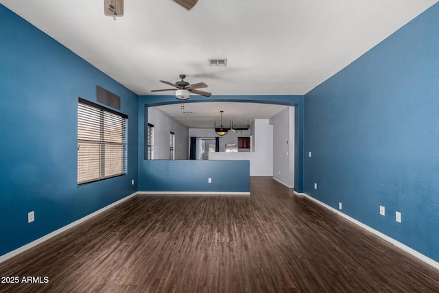 unfurnished living room featuring visible vents, baseboards, dark wood-style floors, and a ceiling fan