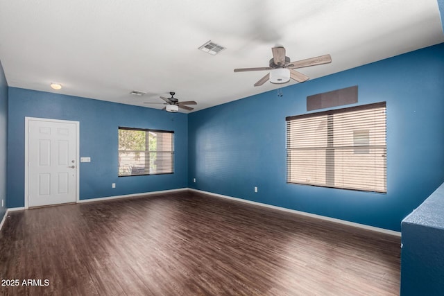 unfurnished room with baseboards, wood finished floors, visible vents, and ceiling fan